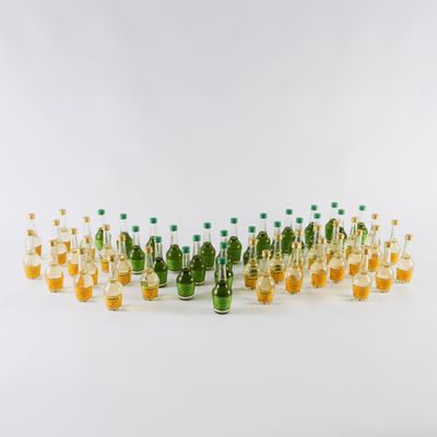 des bouteilles remplies d'un liquide orange et vert sont posées sur une surface blanche