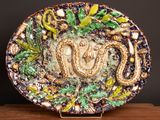 a decorative plate with a snake on it on a wooden stand