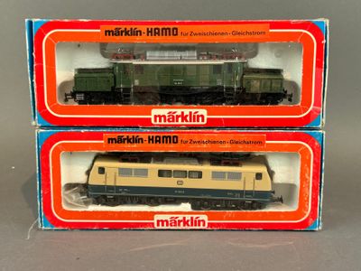 deux boîtes contenant des trains miniatures Märklin posées sur une surface grise