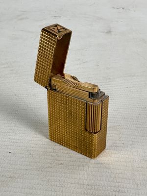 a gold lighter that is sitting on a white surface