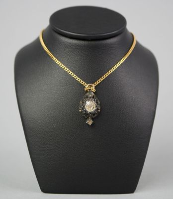 a gold necklace with a black and white stone pendant on a black mannequin