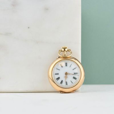 une image représentant une montre de poche en or posée sur un bloc de marbre