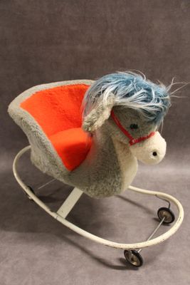 un petit cheval à bascule aux cheveux bleus et à la selle rouge