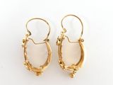 a pair of gold hoop earrings with white stones on a white background