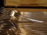 many forks and spoons sitting on a tray in a case