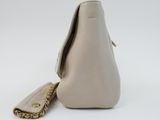 beige leather handbag with gold chain strap on white background