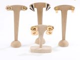 trois paires de boucles d'oreilles plaquées or, présentées sur un présentoir posé sur une surface blanche