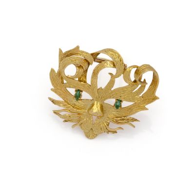 a close up of a gold brooch with green stones