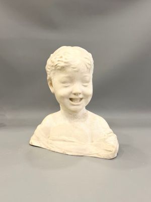 deux sculptures en céramique blanche représentant un garçon et une fille, posées sur une surface grise