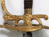 a gold sword with a black handle on a white background