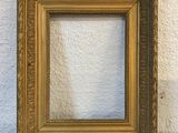 an old picture frame sitting on a table against a white wall