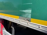 a green and yellow truck with a red bag on the back