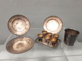 une vitrine sur laquelle sont exposés des assiettes et des tasses en argent