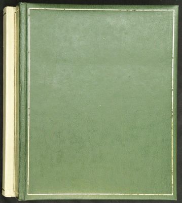 un livre ouvert, à la couverture verte, posé sur une table