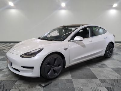 une Tesla Model 3 blanche garée sur un sol carrelé à damier