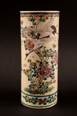 a tall vase with a bird and flowers on it