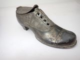 a silver shoe that is sitting on a white surface