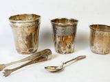 une tasse, une cuillère et un repose-cuillère en argent posés sur une surface blanche