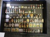 une vitrine posée par terre, remplie de pin's et d'aimants