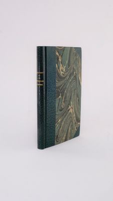 an old book with a green cover sitting on top of a white surface