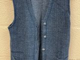 a blue vest hanging on a wall with a wooden hanger