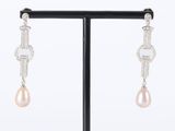 pair of pearl and diamond earrings on a black stand