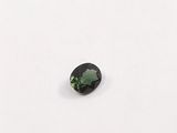 a green tourmaline gems on a white surface