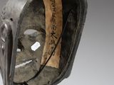 a sculpture of a mask on a stand with a tag