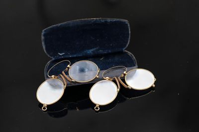 two white and gold earrings in a velvet case on a black surface
