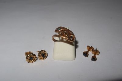 a gold ring and earring set on a white surface