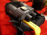 un sac noir muni d'une poignée jaune et sur lequel est posé un paire de jumelles