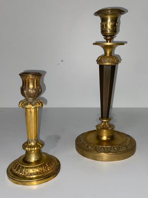 deux bougeoirs en or posés sur une table blanche