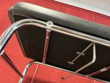 a black leather chair with a metal frame on a red floor