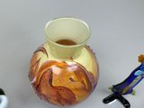 a vase with a design on it next to a small figurine