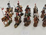 seven figurines of men riding horses with flags on them