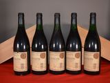 four bottles of wine are lined up on a red cloth