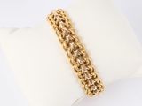 a close up of a gold chain bracelet on a pillow