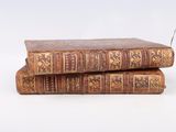 two old books stacked on top of each other on a white surface