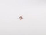 une image représentant un diamant rose posé sur une surface blanche