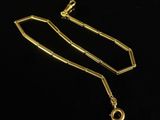a gold necklace with a chain and a clasp on a black background