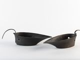 pair of black metal bowls with handles on a white surface