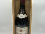 une vieille bouteille de vin dans une caisse en bois posée sur une surface blanche