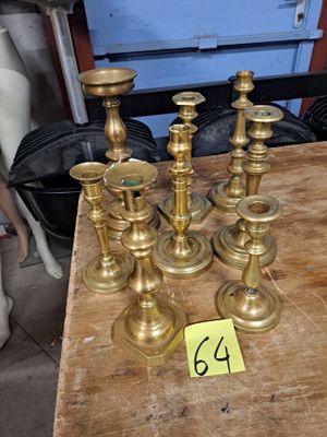 Plusieurs bougies en laiton sont posées sur une table en bois, accompagnées d'une étiquette de prix