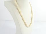 pearl necklace on a mannequin head with a white background