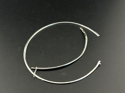 a close up of a pair of silver hoop earrings on a black surface