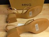 pair of tan leather sandals on a wooden surface next to a box
