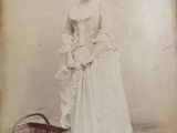 an old photo of a woman in a dress with a basket