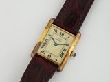 une photo d'une montre-bracelet posée sur une surface blanche, avec un bracelet marron
