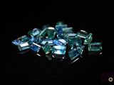 green and blue crystals are scattered on a black surface