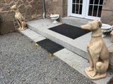 une statue représentant un chien assis sur les marches à l'extérieur d'une maison